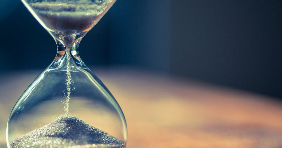 An hourglass sitting on the sand of time